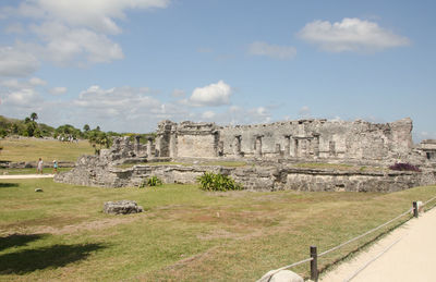 Mayan ruins on field at tulum against sky