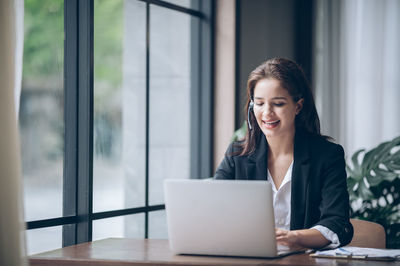 Woman using phone while sitting on table