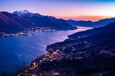 View of lake como at dusk, towards the south, from musso, with the mountains above and the towns.