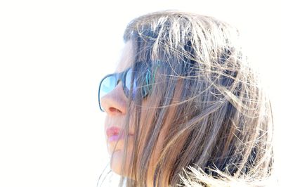 Close-up of woman wearing sunglasses looking away against clear sky during sunny day