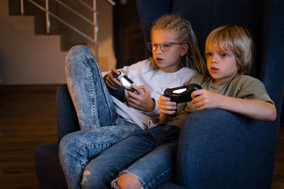 Young woman using mobile phone while sitting on sofa at home