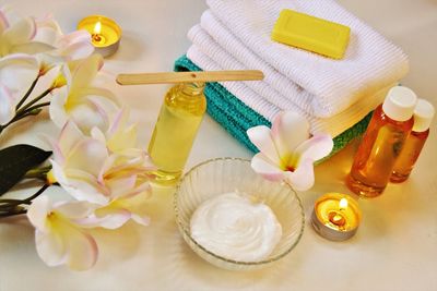 High angle view of flowers with beauty products on table