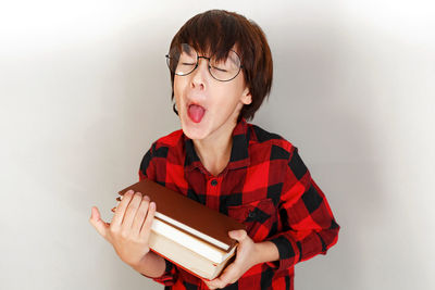 Portrait of young man holding book against white background