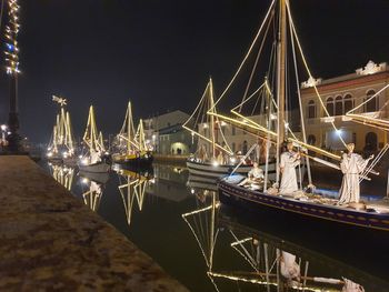 Boats moored at harbor against sky at night