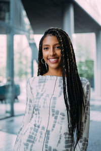 Portrait of smiling young woman with long hair standing outdoors