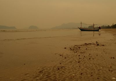 Boat moored on beach against sky