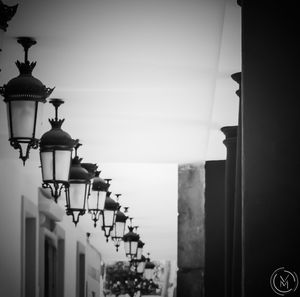 Illuminated street light by building against clear sky