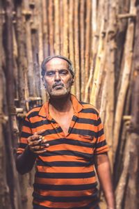 Portrait of man smoking cigarette amidst wooden structure