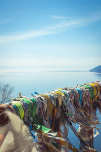 Close-up of multi colored fabrics on railing over sea against sky