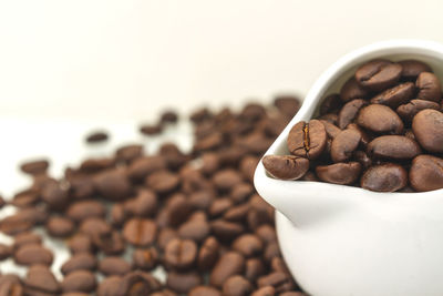 Close-up roasted coffee beans in pitcher against white background