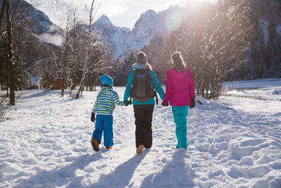 Rear view of women walking in snow during winter