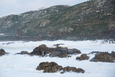 Rocks in sea against mountains