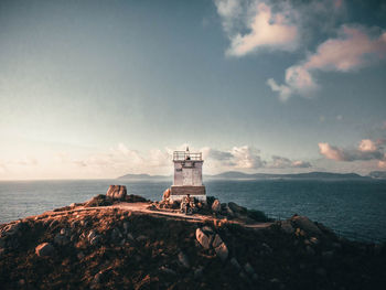 Lighthouse by sea against sky