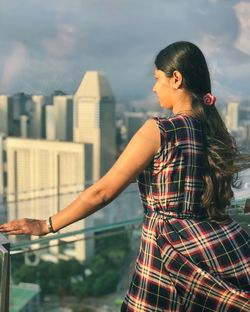 Young woman looking at cityscape against sky