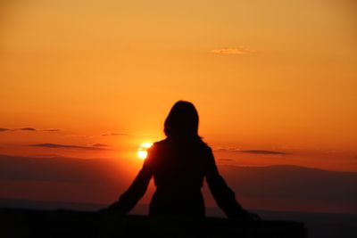 Silhouette woman standing against orange sky