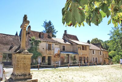 Built structure by trees and buildings against sky