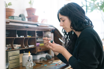 Portrait of female jewler working at home studio with small tools