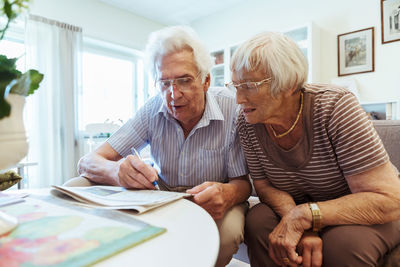 Senior couple doing crossword puzzle in newspaper at nursing home
