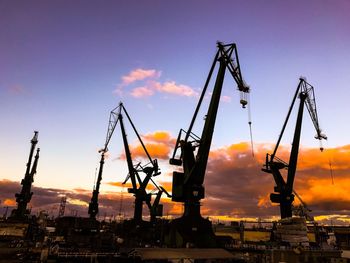 Low angle view of cranes against sky during sunset