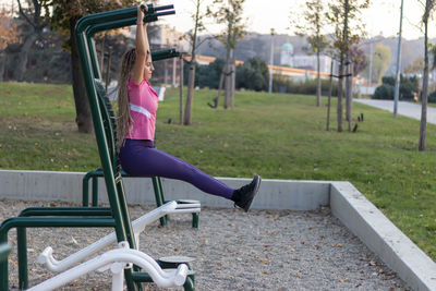 Teen girl using equipment outdoor in the communication with the workout, healthy lifestyle