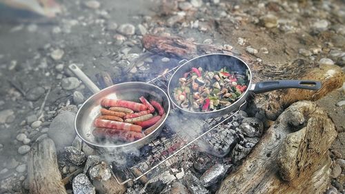 High angle view of sausages and vegetables being cooked on campfire