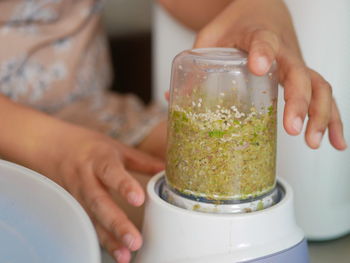 Woman's hands about to take off a blender cup after the food ingredients inside were blended at home