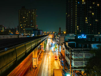 High angle view of illuminated street amidst buildings at night