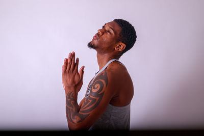 Side view of young man drinking water against white background
