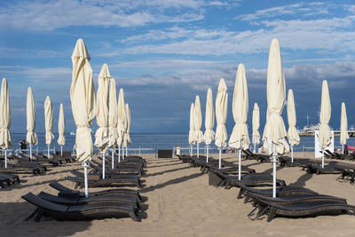 Parasols and lounge chairs at beach against sky