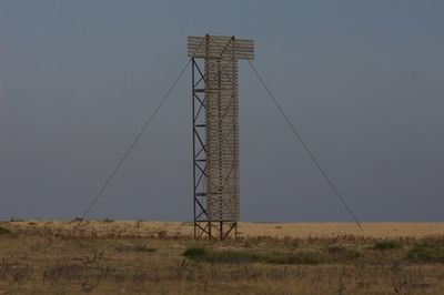 Low angle view of electricity pylon on field