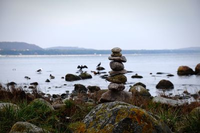 Stack of stones in sea against sky