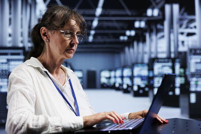Side view of young businesswoman using laptop at office