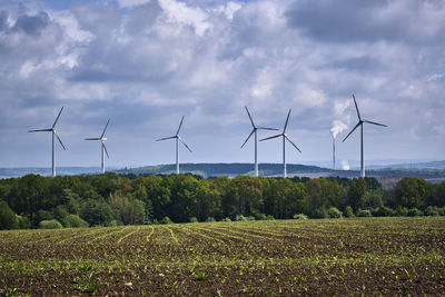 Wind turbines on field against sky