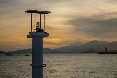 View of lighthouse in sea during sunset