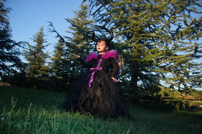 Portrait of woman standing by tree on field