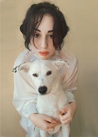 Portrait of woman with dog against wall