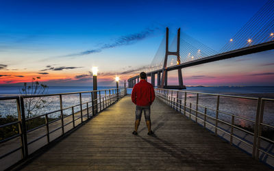 Rear view of man and woman standing on suspension bridge