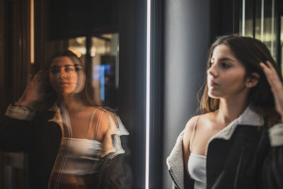 Young woman looking through window