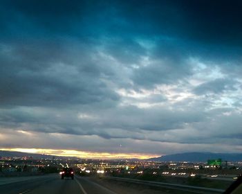 Cars on road against cloudy sky
