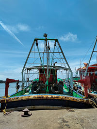 Low angle view of crane by pier against sky