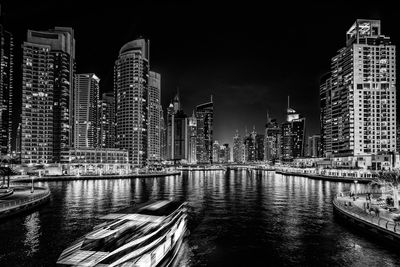 River by illuminated city against sky at night