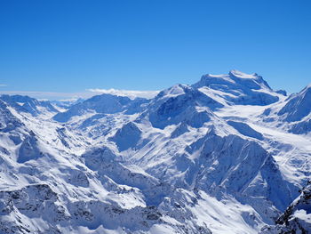 Scenic view of snowcapped mountains against blue sky