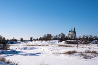 Church by building against clear blue sky during winter