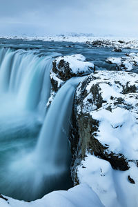 Scenic view of waterfall against sky