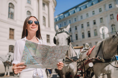 Young woman wearing sunglasses standing on street in city