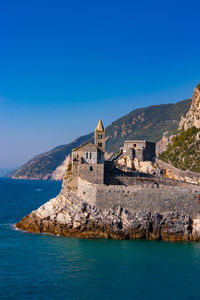 Buildings by sea against blue sky