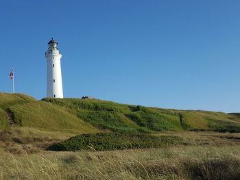 Lighthouse on field against sky