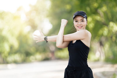 Portrait of smiling young woman standing against blurred background