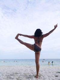 Rear view of woman standing on beach against sky