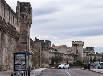 Cars on road by buildings against sky in city